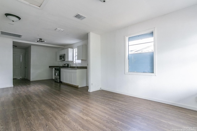 unfurnished living room featuring dark wood-style floors, baseboards, visible vents, and a sink