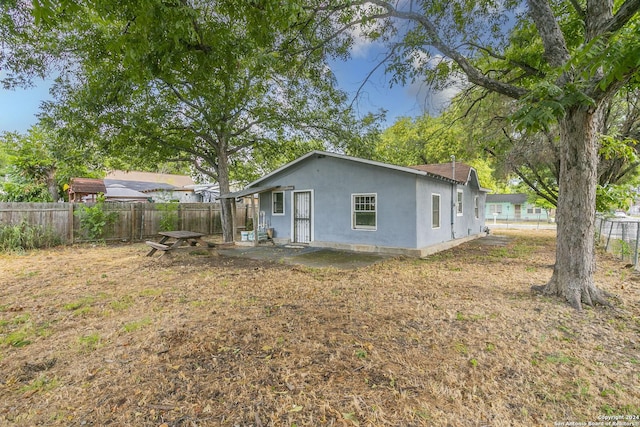 back of house with a fenced backyard, a patio, and stucco siding