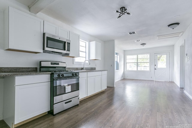 kitchen with visible vents, white cabinets, dark wood finished floors, stainless steel appliances, and a sink