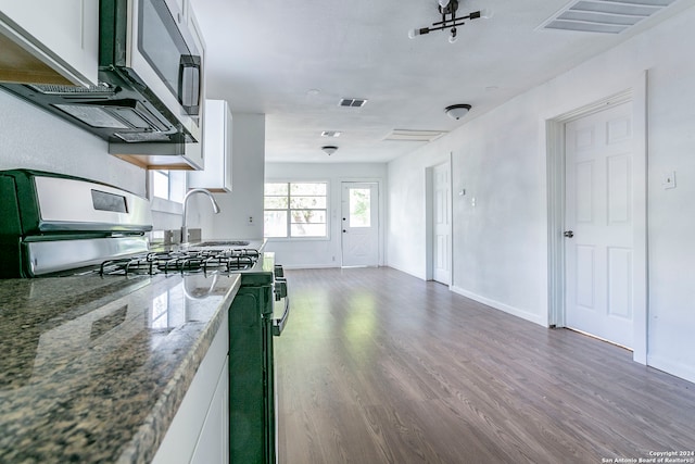 kitchen with dark wood-type flooring, appliances with stainless steel finishes, dark stone countertops, and white cabinetry