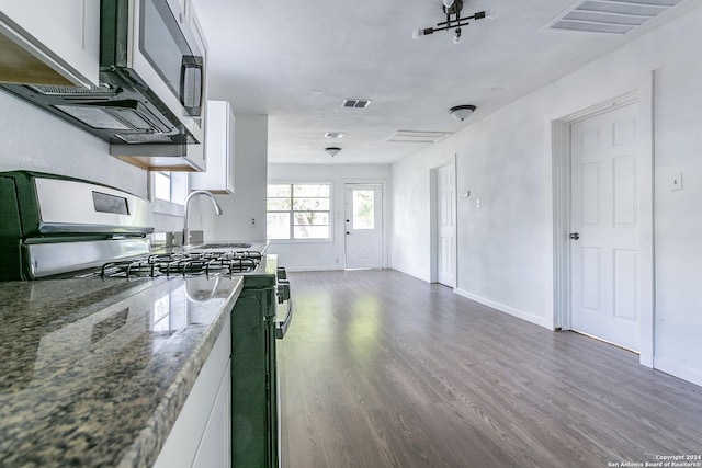 kitchen with stainless steel gas stove, visible vents, white cabinets, and dark wood-style flooring