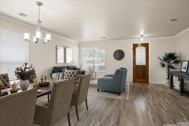 dining space with ornamental molding, a textured ceiling, a chandelier, and hardwood / wood-style floors