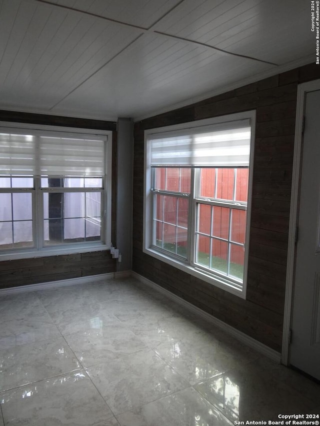 unfurnished room featuring wooden walls