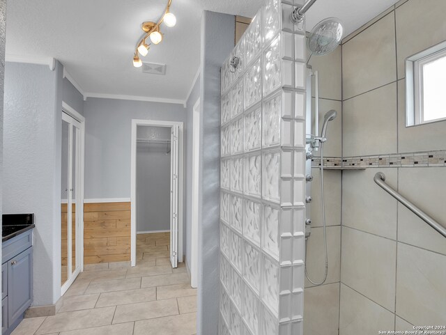 bathroom with a shower, vanity, a textured ceiling, tile patterned flooring, and ornamental molding