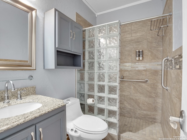 bathroom with a tile shower, ornamental molding, vanity, and toilet