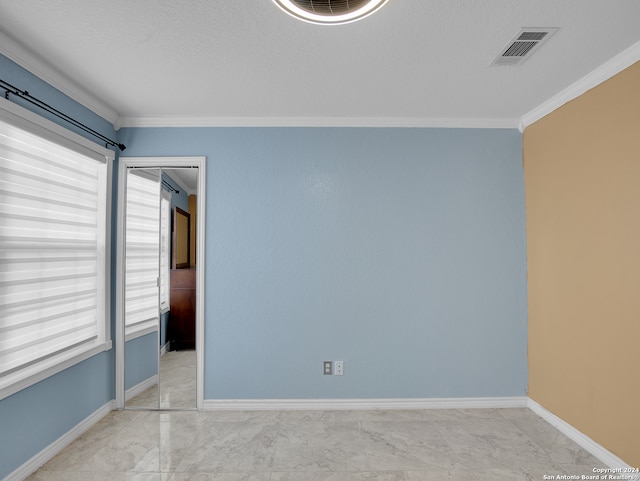 empty room featuring a textured ceiling and ornamental molding