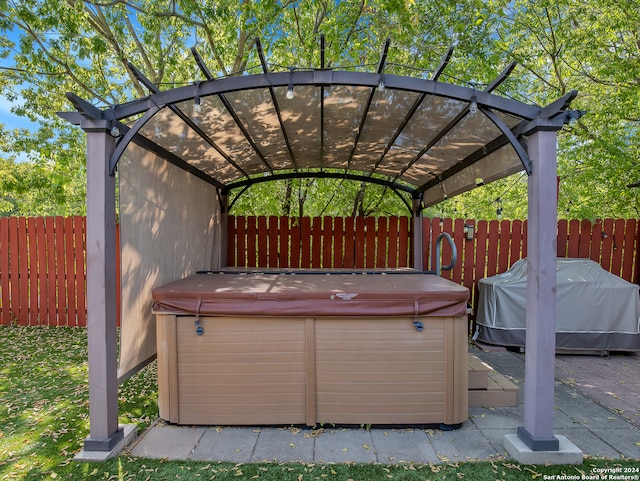 view of patio with area for grilling, a pergola, and a hot tub