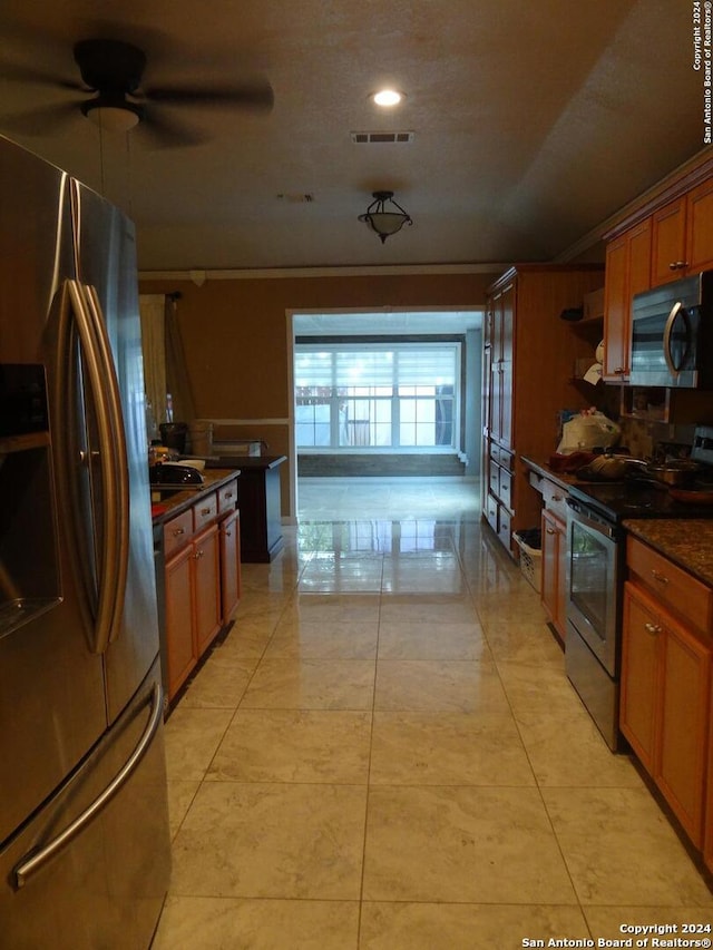 kitchen featuring light tile patterned floors, crown molding, ceiling fan, and stainless steel appliances