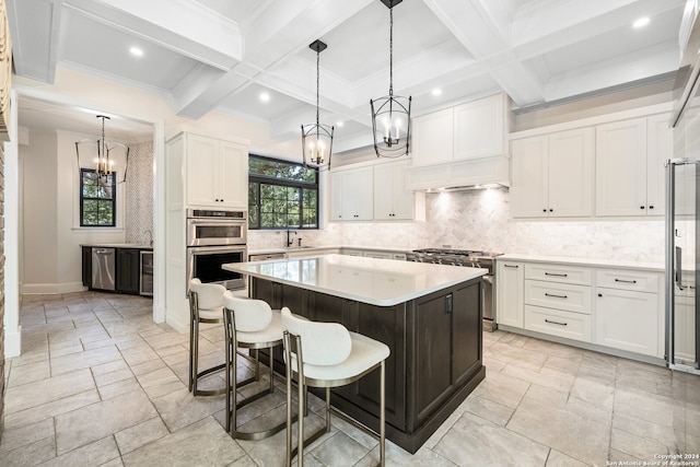 kitchen featuring a center island, beam ceiling, white cabinetry, coffered ceiling, and stainless steel appliances