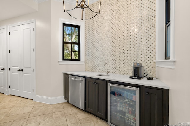 bar featuring ornamental molding, sink, stainless steel dishwasher, beverage cooler, and an inviting chandelier