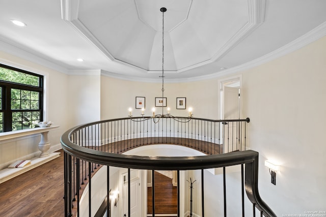 stairway with ornamental molding, hardwood / wood-style floors, a tray ceiling, and a notable chandelier