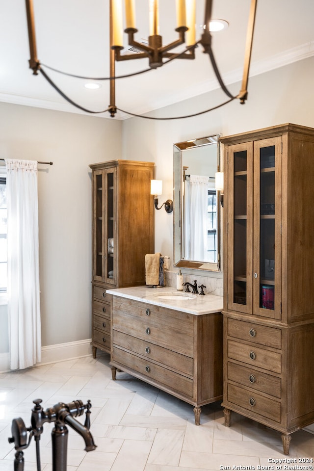 bathroom with ornamental molding, vanity, and a notable chandelier