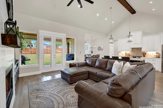 living area featuring french doors, a ceiling fan, high vaulted ceiling, light wood-type flooring, and beamed ceiling