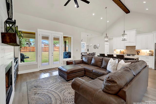 living room featuring french doors, light hardwood / wood-style floors, ceiling fan, high vaulted ceiling, and beam ceiling