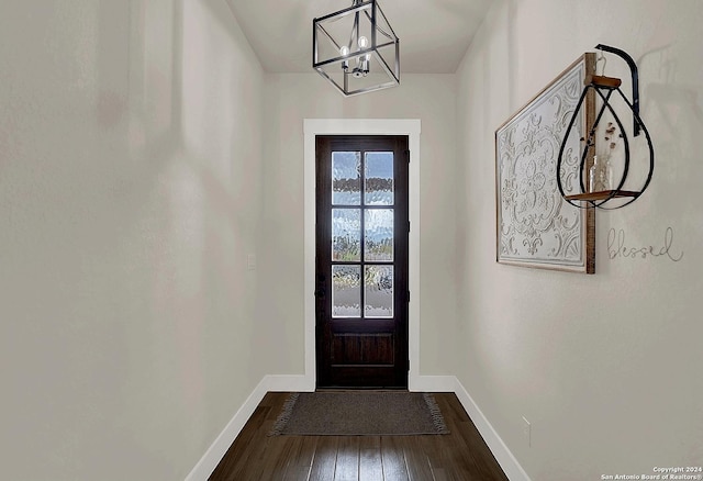 doorway to outside featuring an inviting chandelier, wood-type flooring, and baseboards