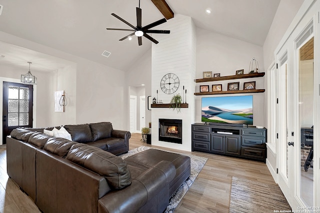 living room featuring light hardwood / wood-style flooring, beam ceiling, a large fireplace, high vaulted ceiling, and ceiling fan