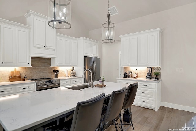 kitchen featuring lofted ceiling, stainless steel appliances, sink, and light stone counters