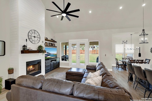 living area with light wood-type flooring, plenty of natural light, a fireplace, and high vaulted ceiling