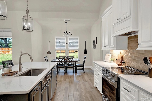 kitchen with appliances with stainless steel finishes, white cabinets, a sink, and a notable chandelier