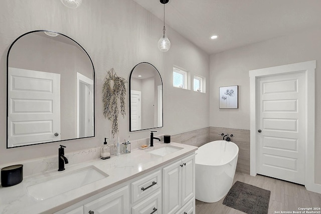 bathroom with a soaking tub, a sink, tile walls, and double vanity