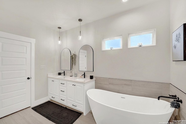 bathroom featuring double vanity, a soaking tub, tile walls, and a sink