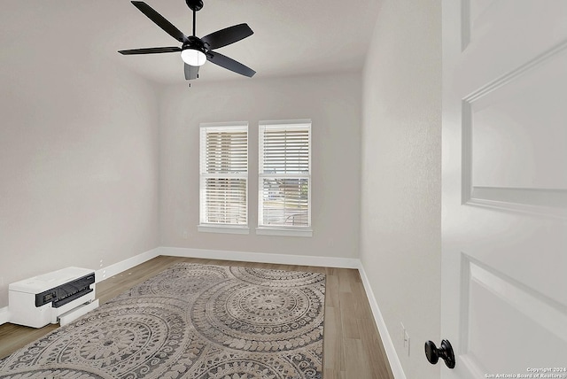 unfurnished room featuring wood finished floors, a ceiling fan, and baseboards