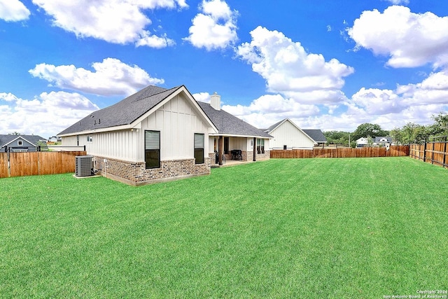 rear view of house with brick siding, a yard, a chimney, board and batten siding, and a fenced backyard