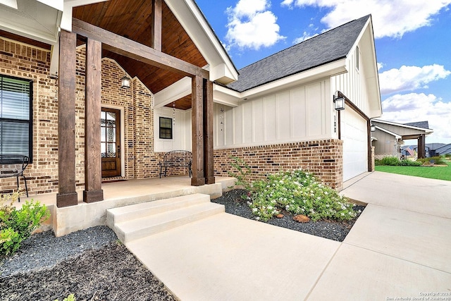 view of exterior entry featuring board and batten siding, brick siding, a porch, and a garage