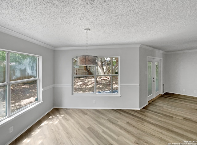 unfurnished dining area with a textured ceiling, ornamental molding, and hardwood / wood-style floors