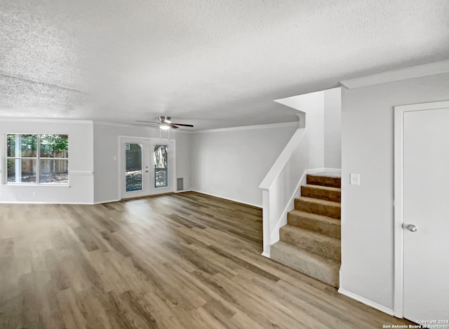 unfurnished living room with a textured ceiling, ceiling fan, wood-type flooring, and french doors