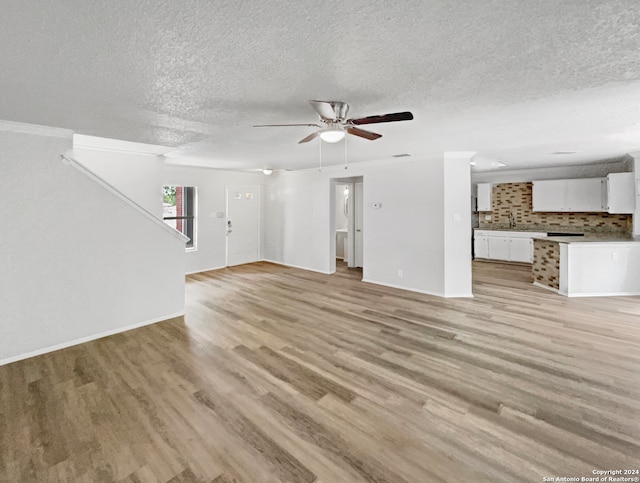 unfurnished living room featuring a textured ceiling, light hardwood / wood-style flooring, and ceiling fan