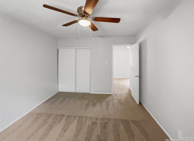 unfurnished bedroom with light carpet, ceiling fan, and a closet