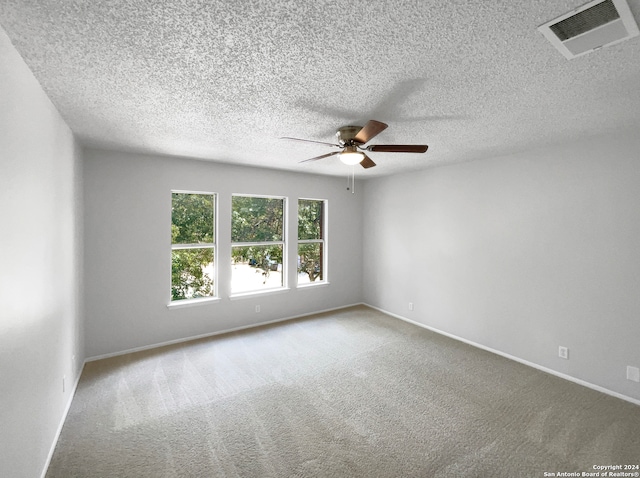 unfurnished room featuring a textured ceiling, ceiling fan, and carpet floors