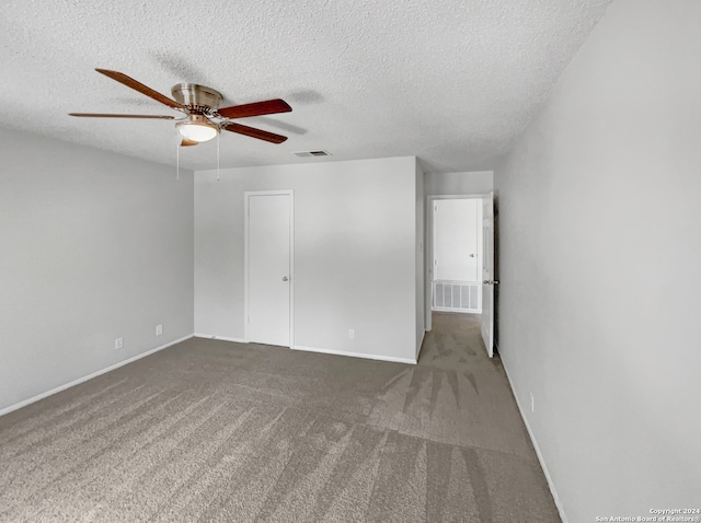 empty room featuring a textured ceiling, ceiling fan, and carpet floors