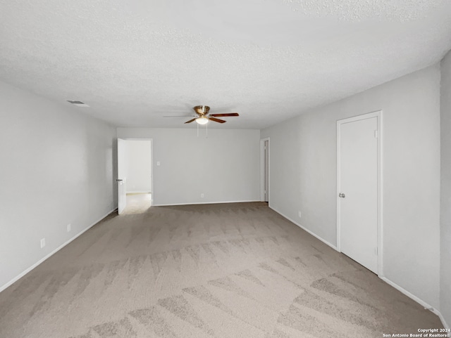 unfurnished room with a textured ceiling, ceiling fan, and light carpet