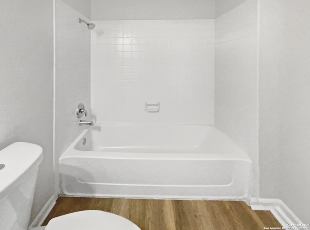 bathroom with tiled shower / bath combo, toilet, and hardwood / wood-style flooring