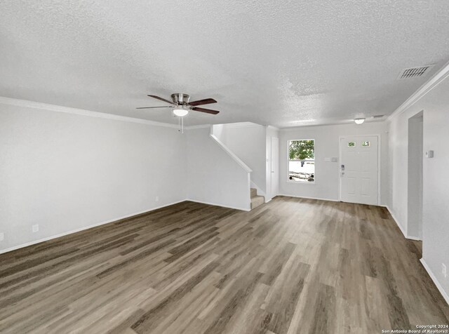 unfurnished living room featuring stairs, ornamental molding, wood finished floors, and visible vents