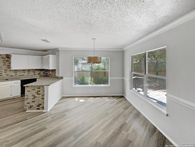 kitchen featuring crown molding, decorative backsplash, hanging light fixtures, white cabinets, and light hardwood / wood-style floors