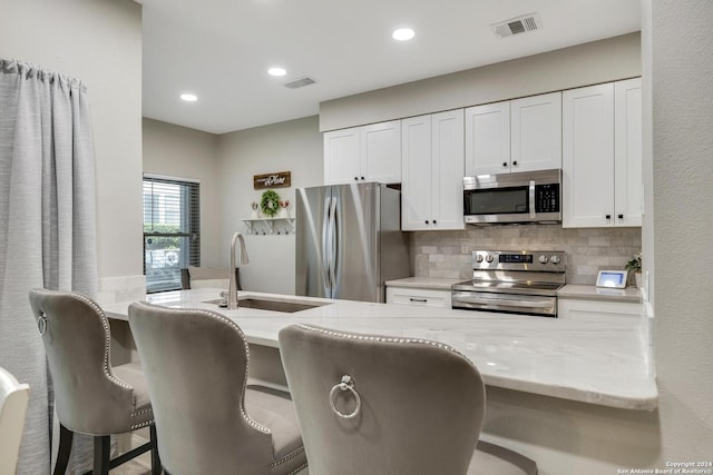 kitchen with stainless steel appliances, visible vents, backsplash, and light stone counters