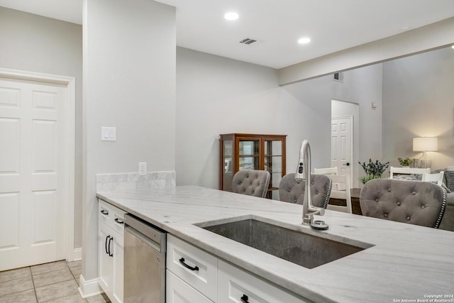 kitchen with dishwasher, light stone counters, open floor plan, white cabinetry, and a sink