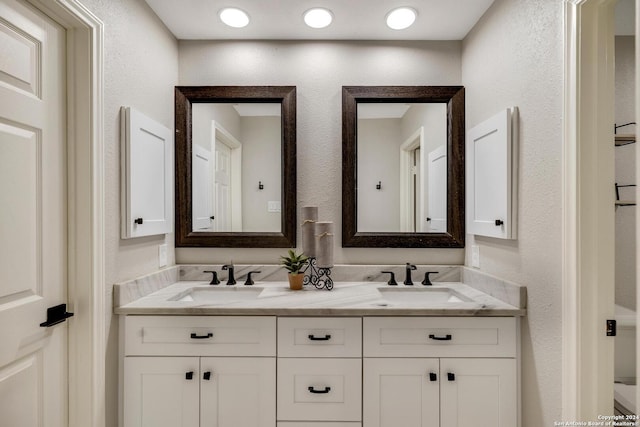 bathroom featuring double vanity, a sink, and a textured wall