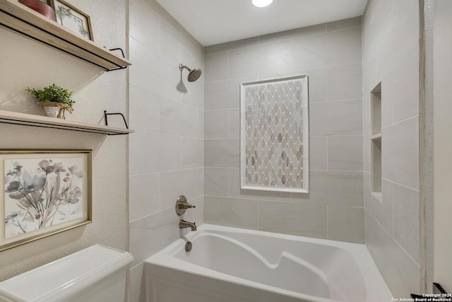 bathroom featuring a textured wall, toilet, and shower / bathtub combination