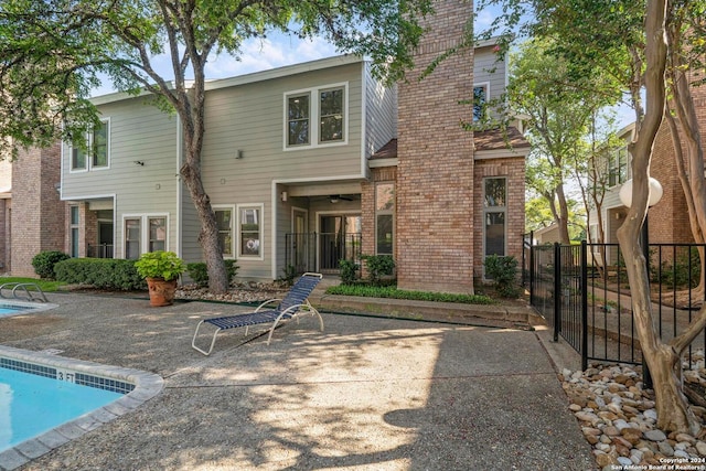 back of property with a fenced in pool and a patio