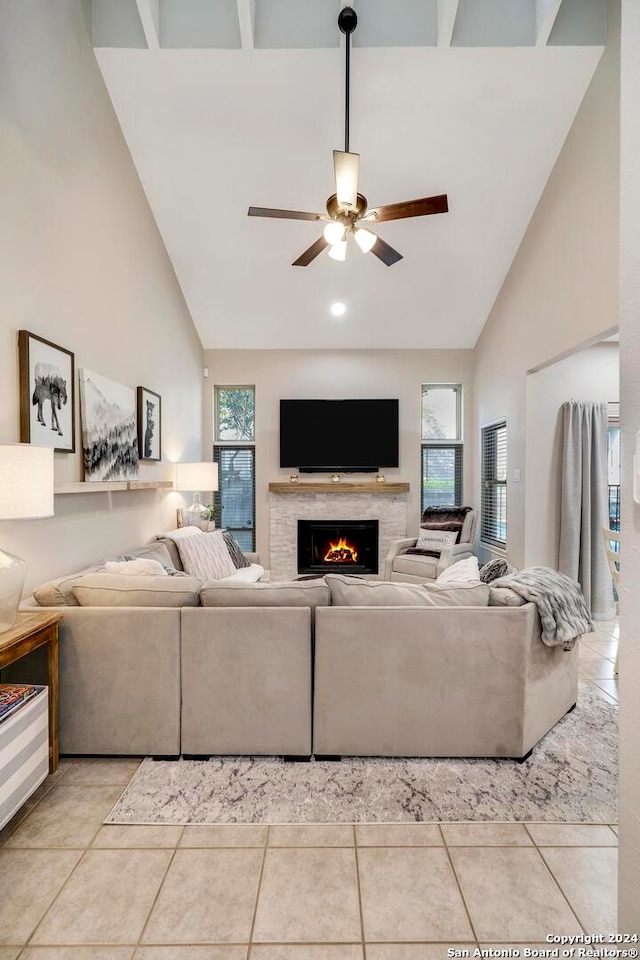 tiled living room with ceiling fan and high vaulted ceiling