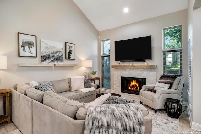 living room featuring high vaulted ceiling, light tile patterned floors, and a stone fireplace