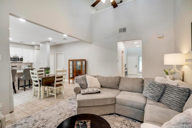 tiled living room featuring ceiling fan and a towering ceiling