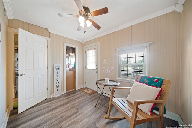 living area with hardwood / wood-style floors, crown molding, and ceiling fan