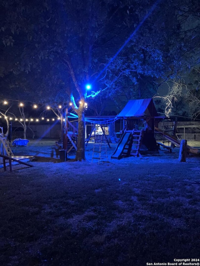 yard at night featuring a playground