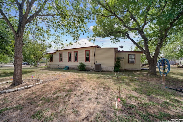 back of house with cooling unit and a yard