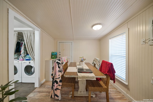 dining area featuring hardwood / wood-style floors, washer and clothes dryer, and wood walls